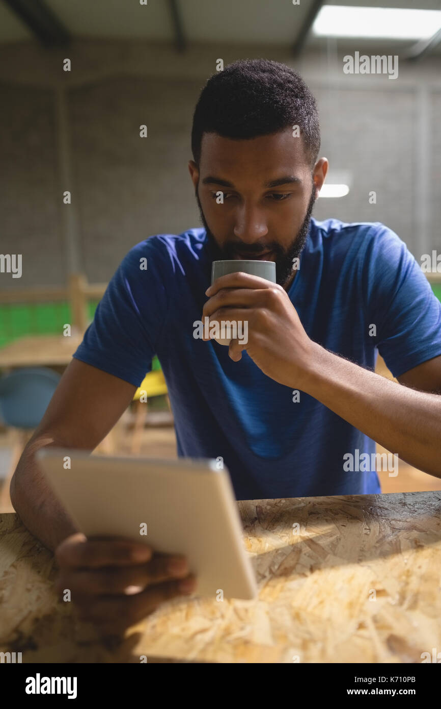 Young man having coffee while using tablet computer at table in cafe Stock Photo
