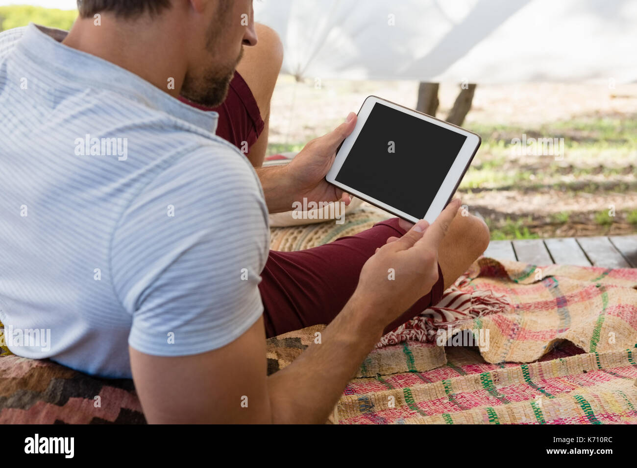 Relaxed young man using digital tablet in tent Stock Photo