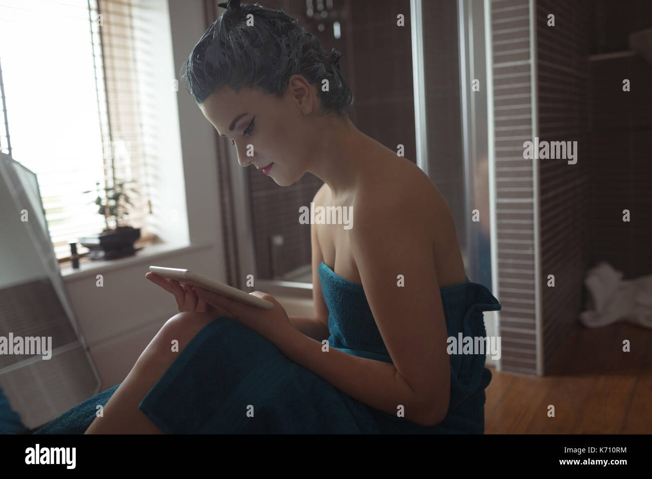 Young woman using digital tablet in bathroom at home Stock Photo