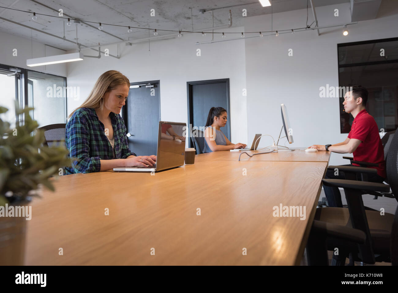 Young business colleagues using technologies at table in office Stock Photo