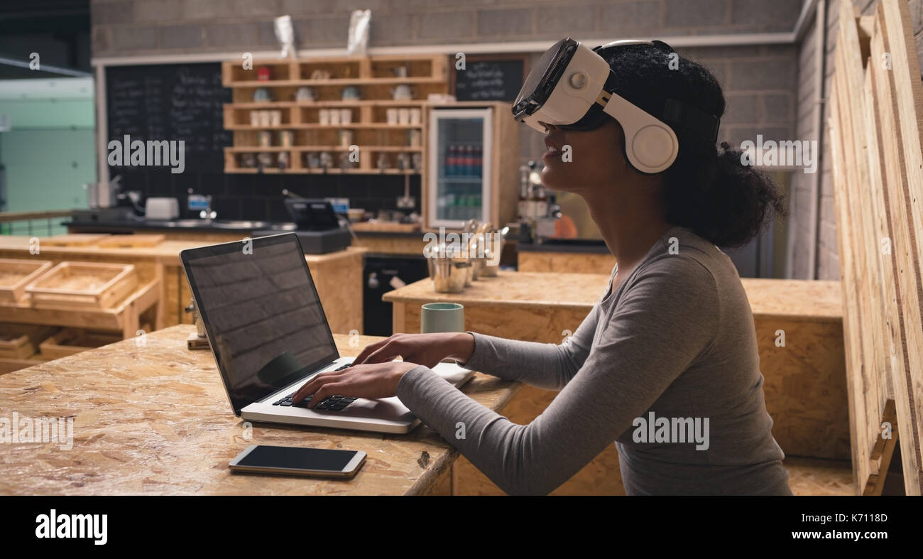 Woman using virtual reality headset while working on laptop in cafÃƒÂ© Stock Photo