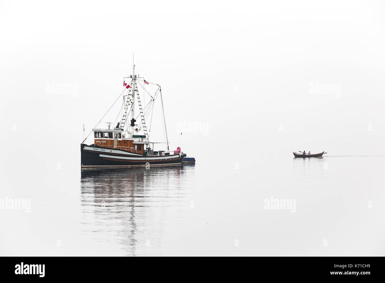 Fishing boat near Port Townsend during Wooden Boat Show in fog with row boat. Stock Photo