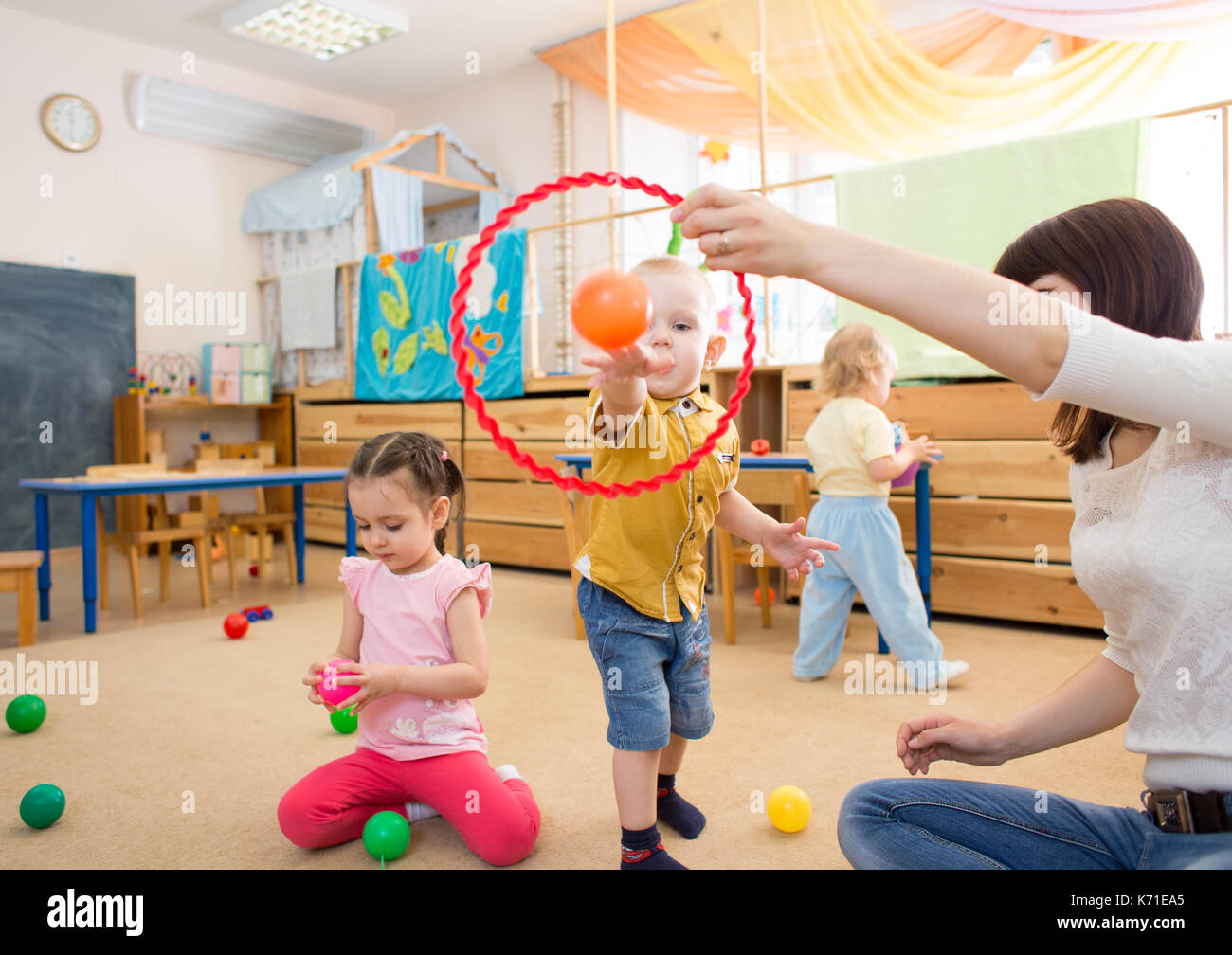 Happy children playing with ball and ring in kindergarten Stock Photo