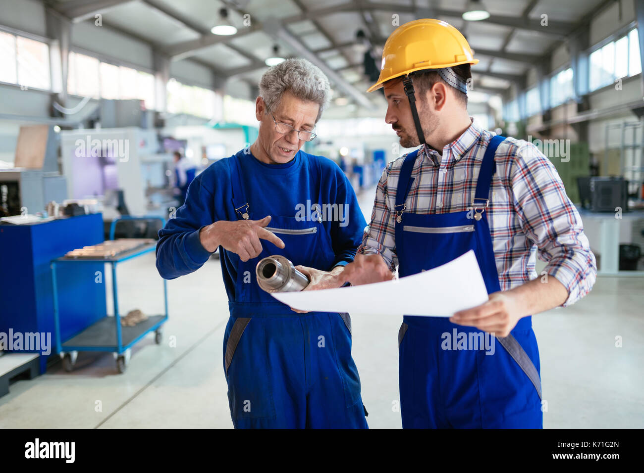Engineer Teaching Apprentices To Use Computerized cnc metal processing machines Stock Photo