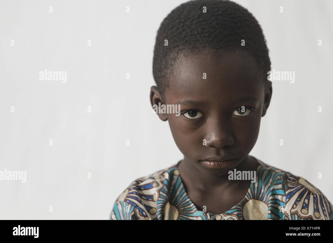 Angry young African boy isolated on white, showing his face for a portrait Stock Photo