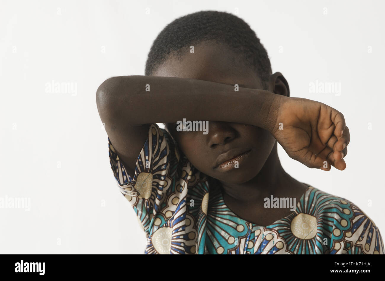 Little African boy asks for help by covering his face with his arm ...