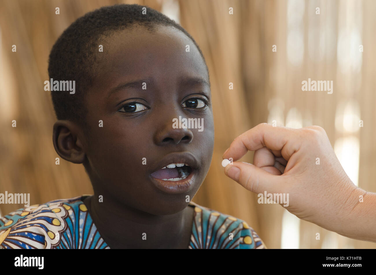 White doctor gives a pill to a little black African boy Stock Photo