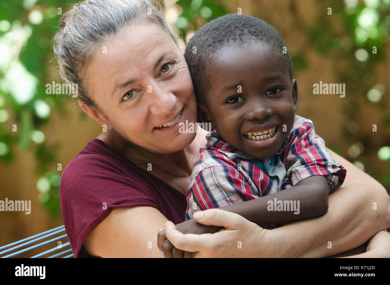Adoption symbol - Woman adopts a little African boy Stock Photo