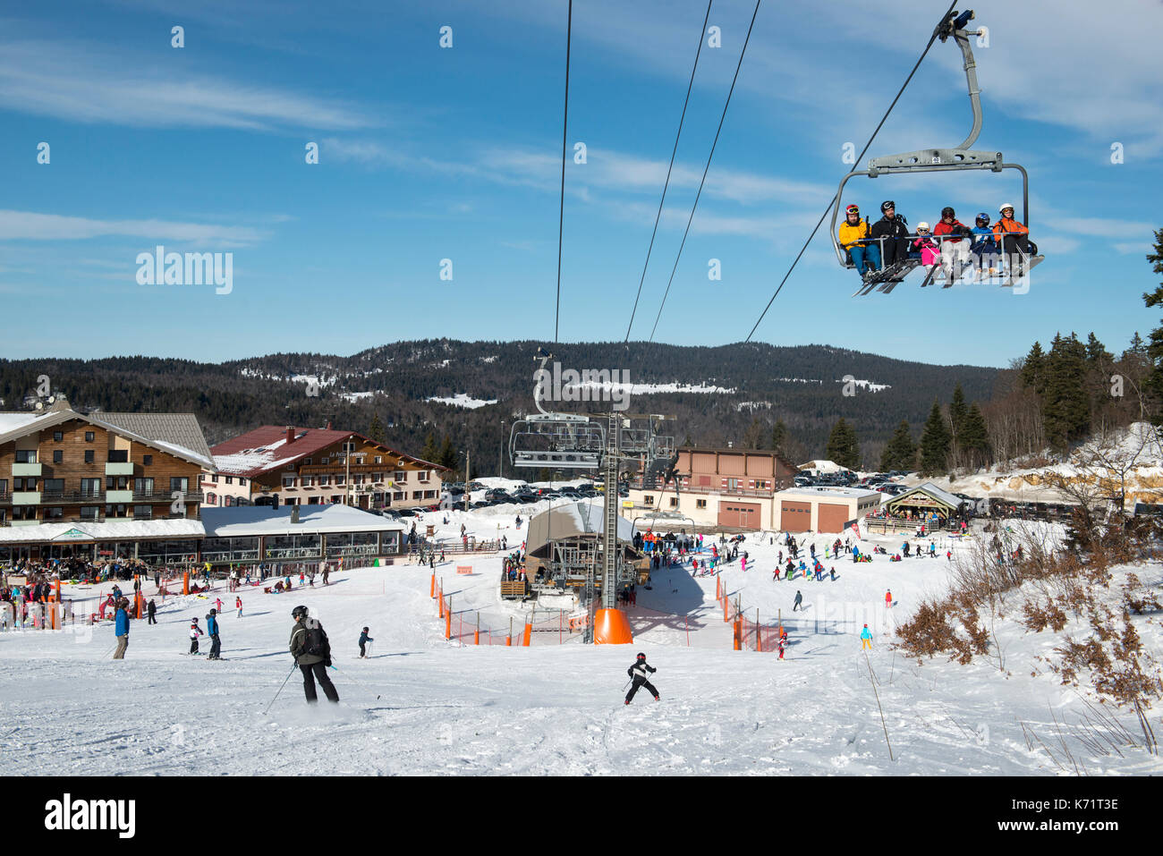 Skiers sitting in a chair lift from La Faucille to Mont Rond, Jura mountains, France Stock Photo