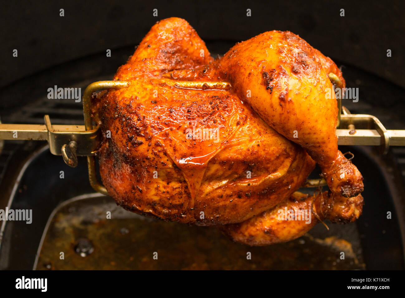 Charred rotisserie chicken over open flames in a barbecue. room for