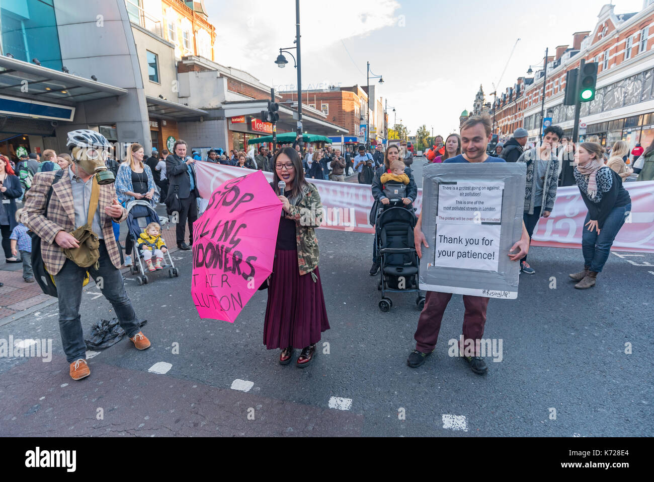 London, UK. 14th September 2017. Campaigners from 'Stop Killing Londoners' stand on the crossing at Brixton Underground station to block the road in a protest against London's excessive air pollution, due mainly to traffic. The air on the Brixton Road breaches the annual pollution limit in only 5 days, roughly 70 times the limit per year. Toxic air pollution results in 10,000 premature deaths in London each year and is particularly harmful to the elderly and the very young. To cut the disruption to traffic they moved out of the road after around five minutes, allowed the traffic build up to mo Stock Photo