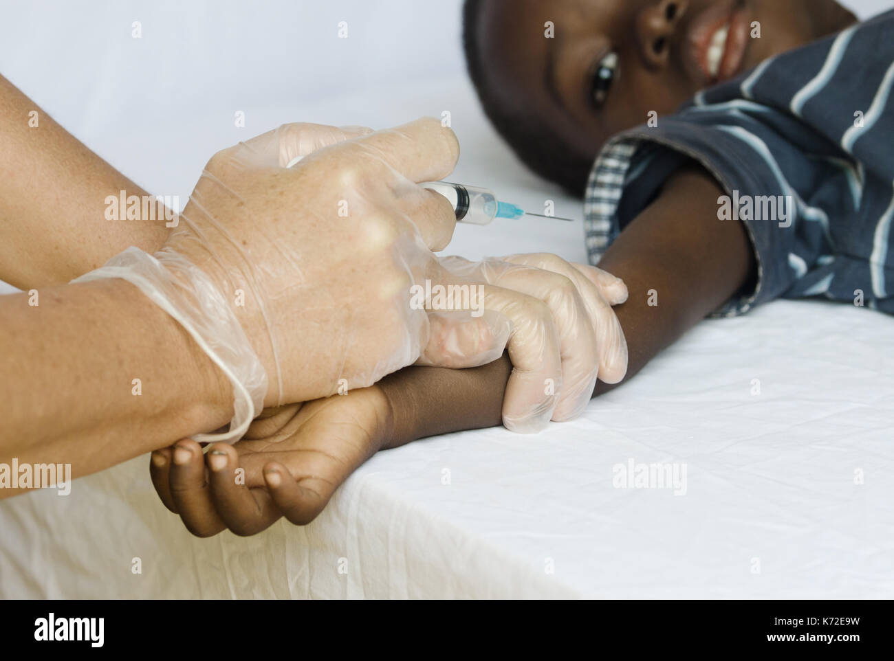 Little African Boy Getting Needle Injection from White Nurse Woman Stock Photo