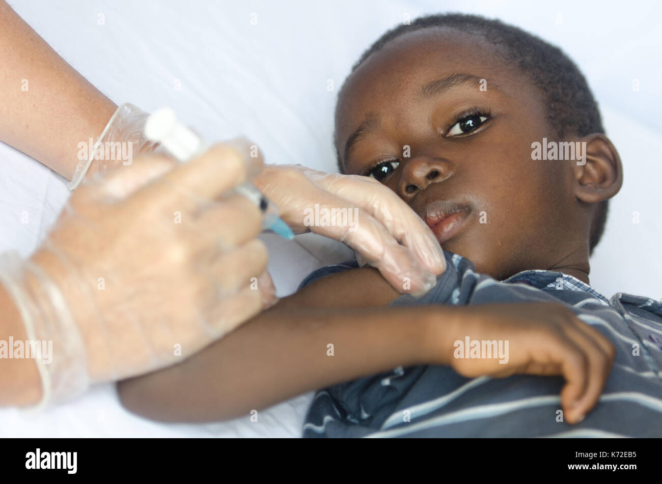 Sad African boy is worried about getting an injection for his health as a vaccination Stock Photo