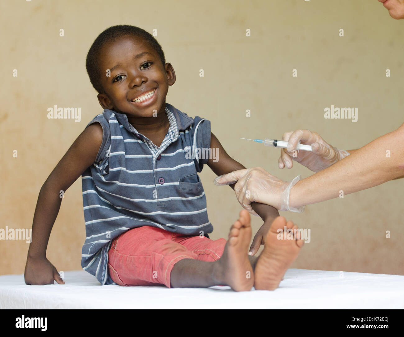 Full body shot of a happy African black child getting a needle injection as a medical vaccination Stock Photo