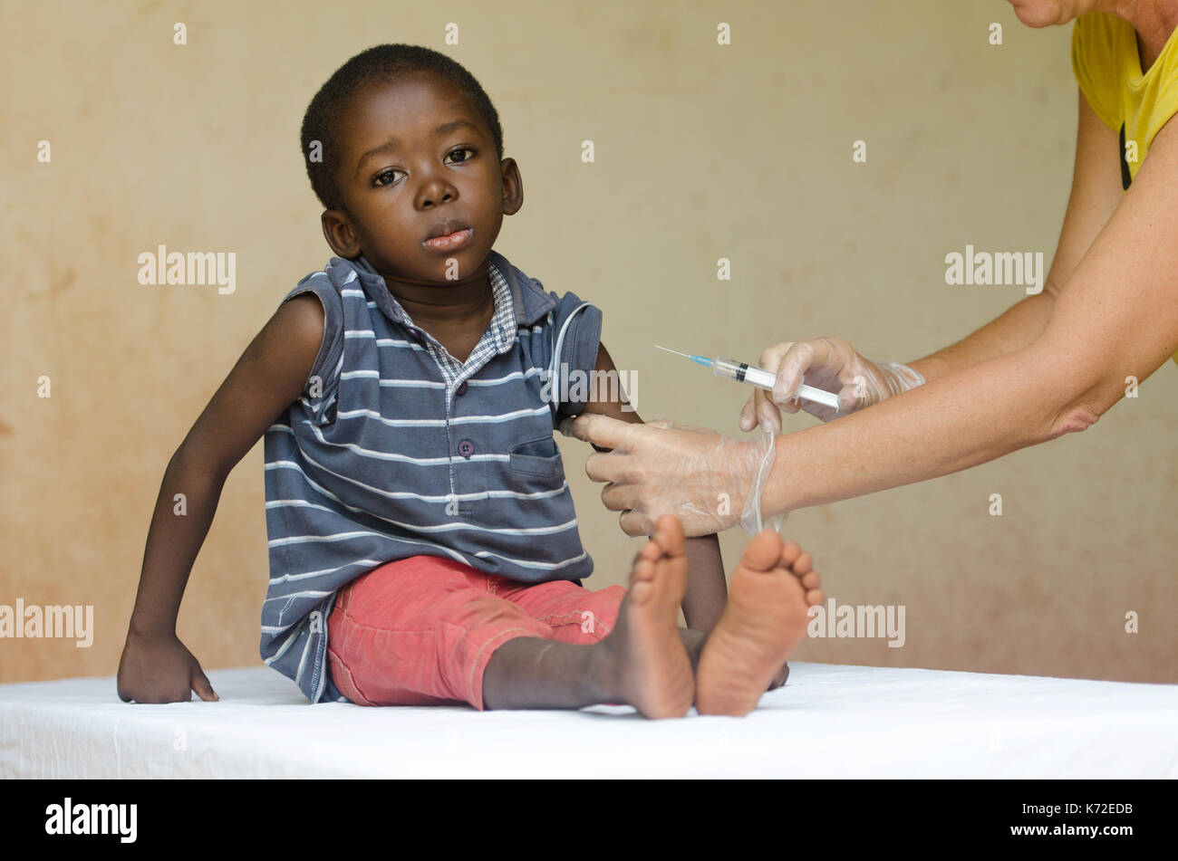 Sad African boy ready to get an injection from a volunteer nurse in Bamako, Mali Stock Photo