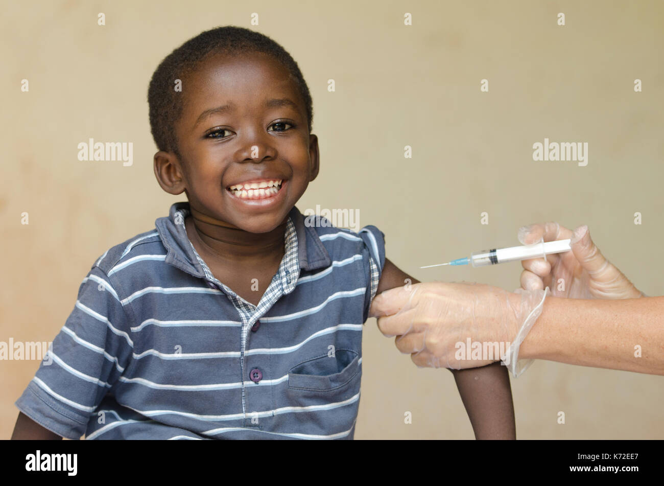 Smiling African boy sitting whilst getting an injection from an European Volunteer Stock Photo