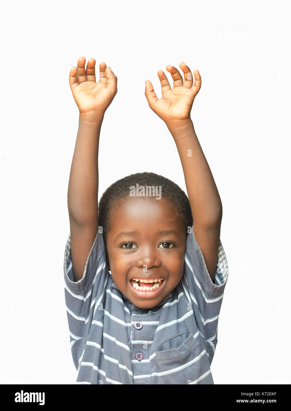 Little African boy holding his hands up in the air whilst laughing and