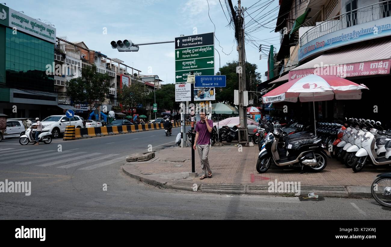 Street Corner Road Signs in Phnom Penh Cambodia man taking on mobile