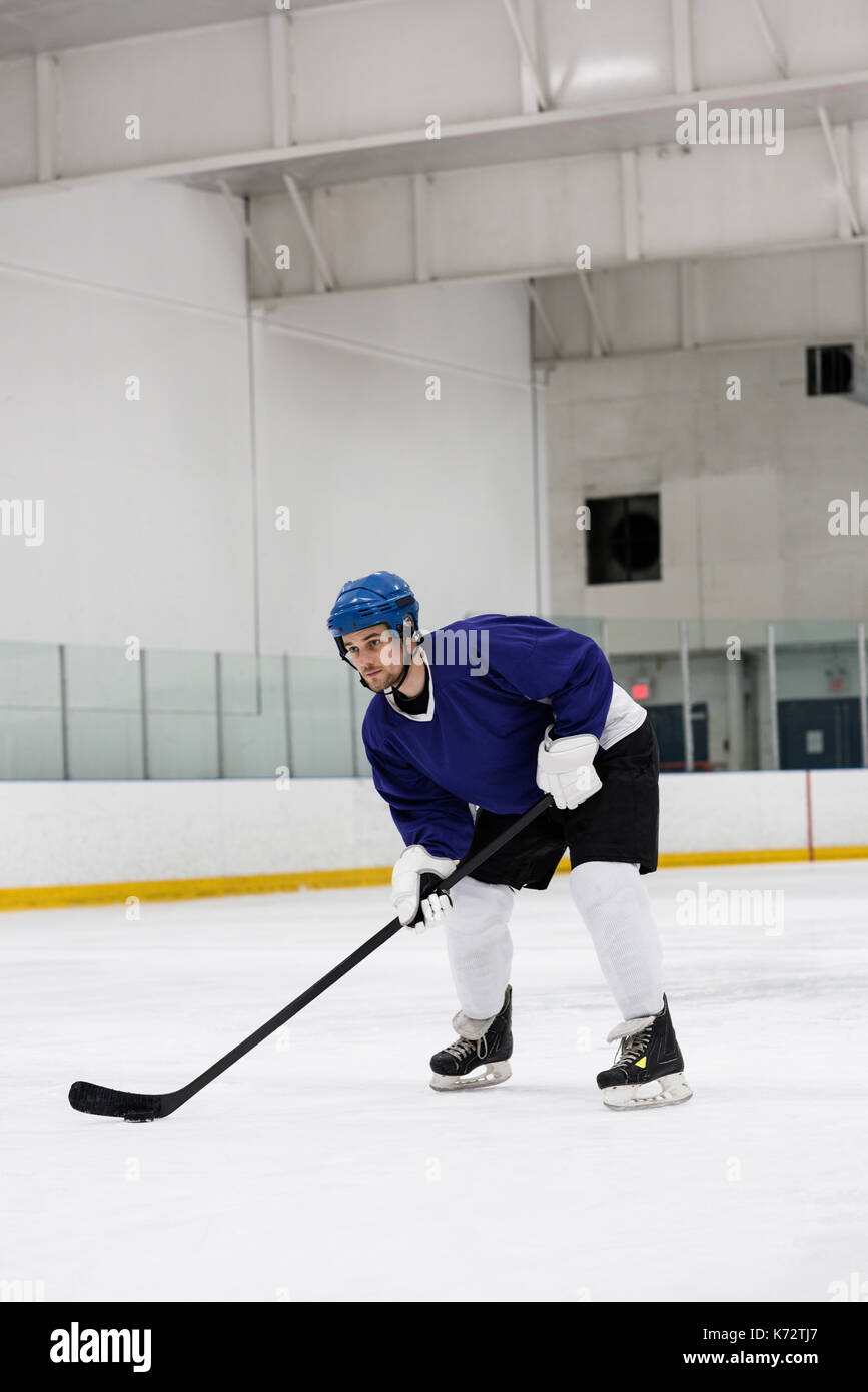 Full length of determined male player practicing ice hockey at rink
