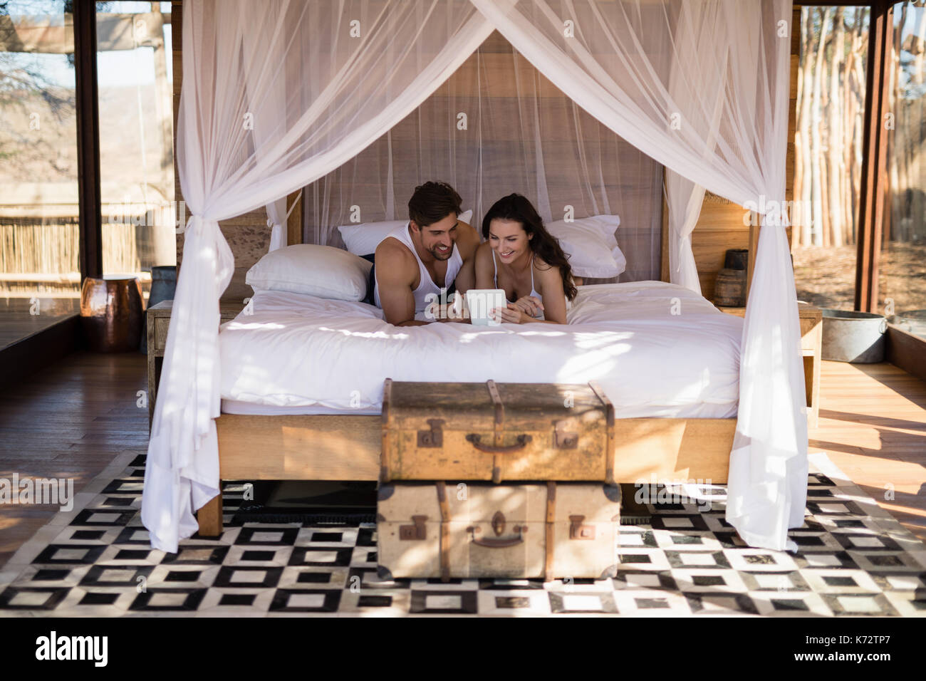 Smiling couple using digital tablet on bed in cottage Stock Photo