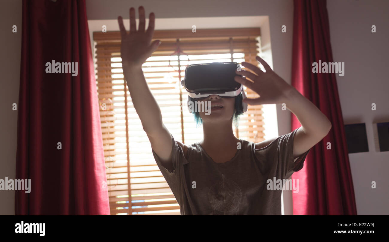 Young woman gesturing while using virtual reality headset at home Stock Photo