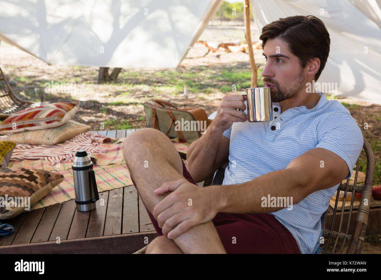 Thoughtful young man drinking coffee in tent Stock Photo