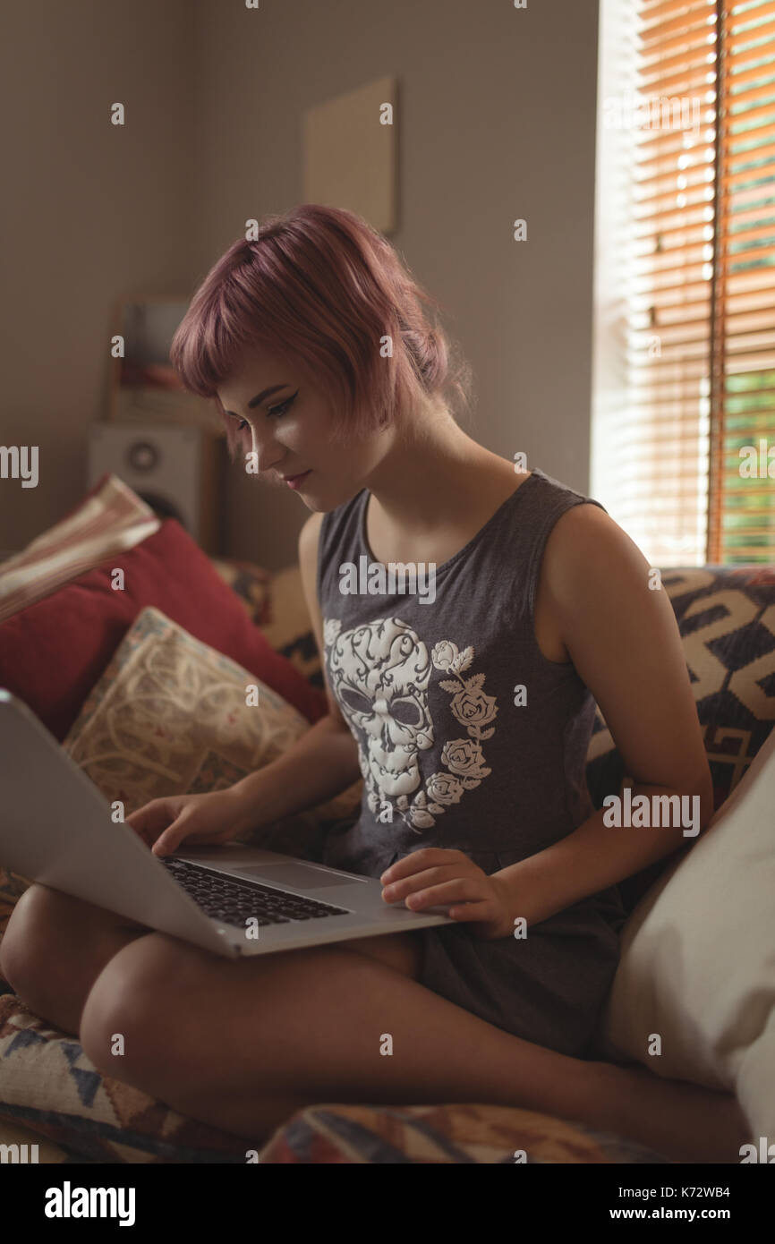 Young woman using laptop on sofa at home Stock Photo
