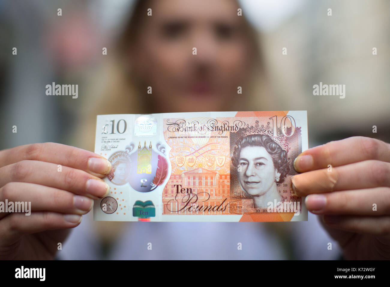 A woman holds a new ten pound note, featuring Jane Austen, in Birmingham High Street. Stock Photo