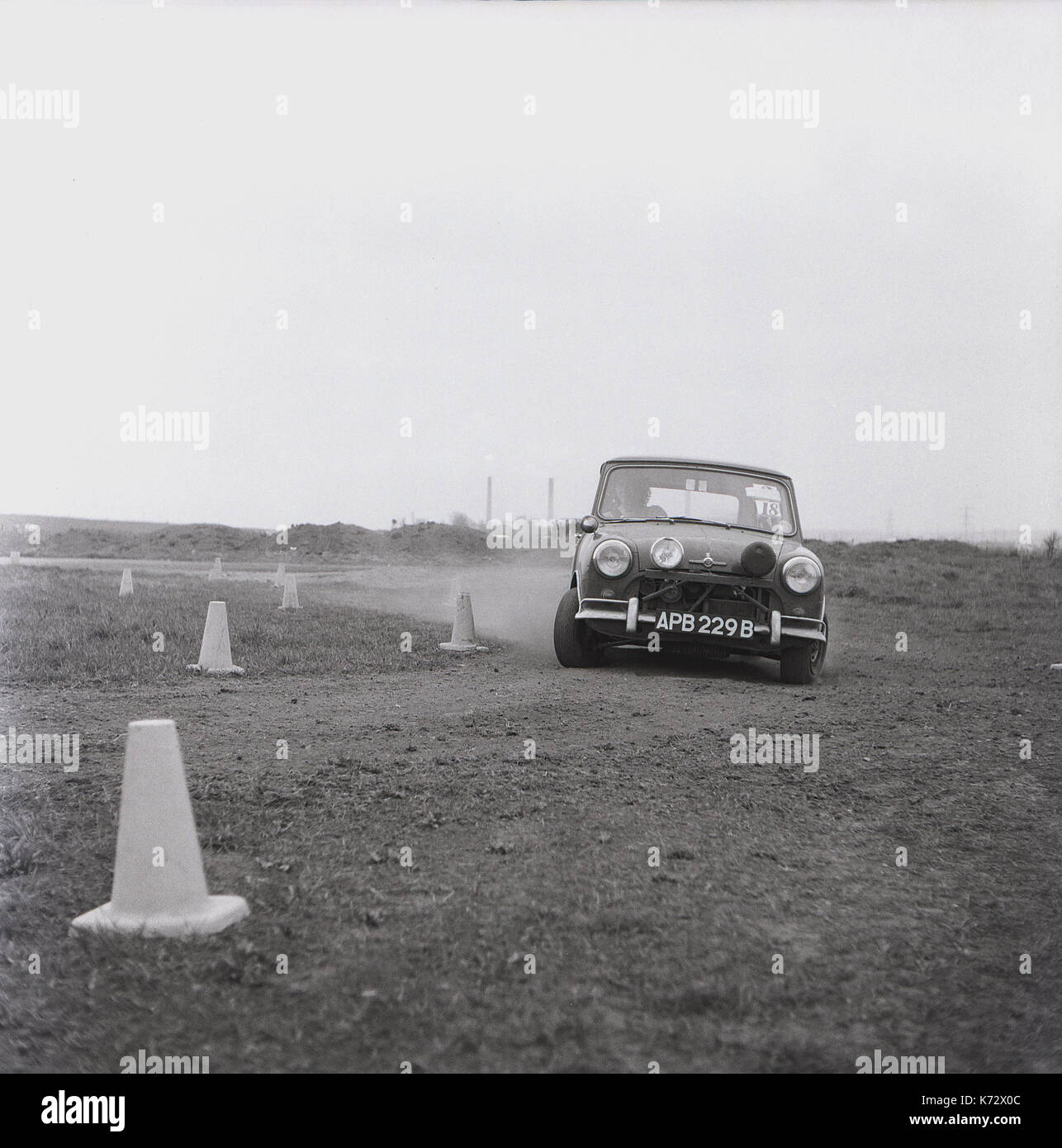 1970s, historical, a specially modified works mini taking a corner at speed while racing on a gravel test track with cones marking the course, England. Stock Photo