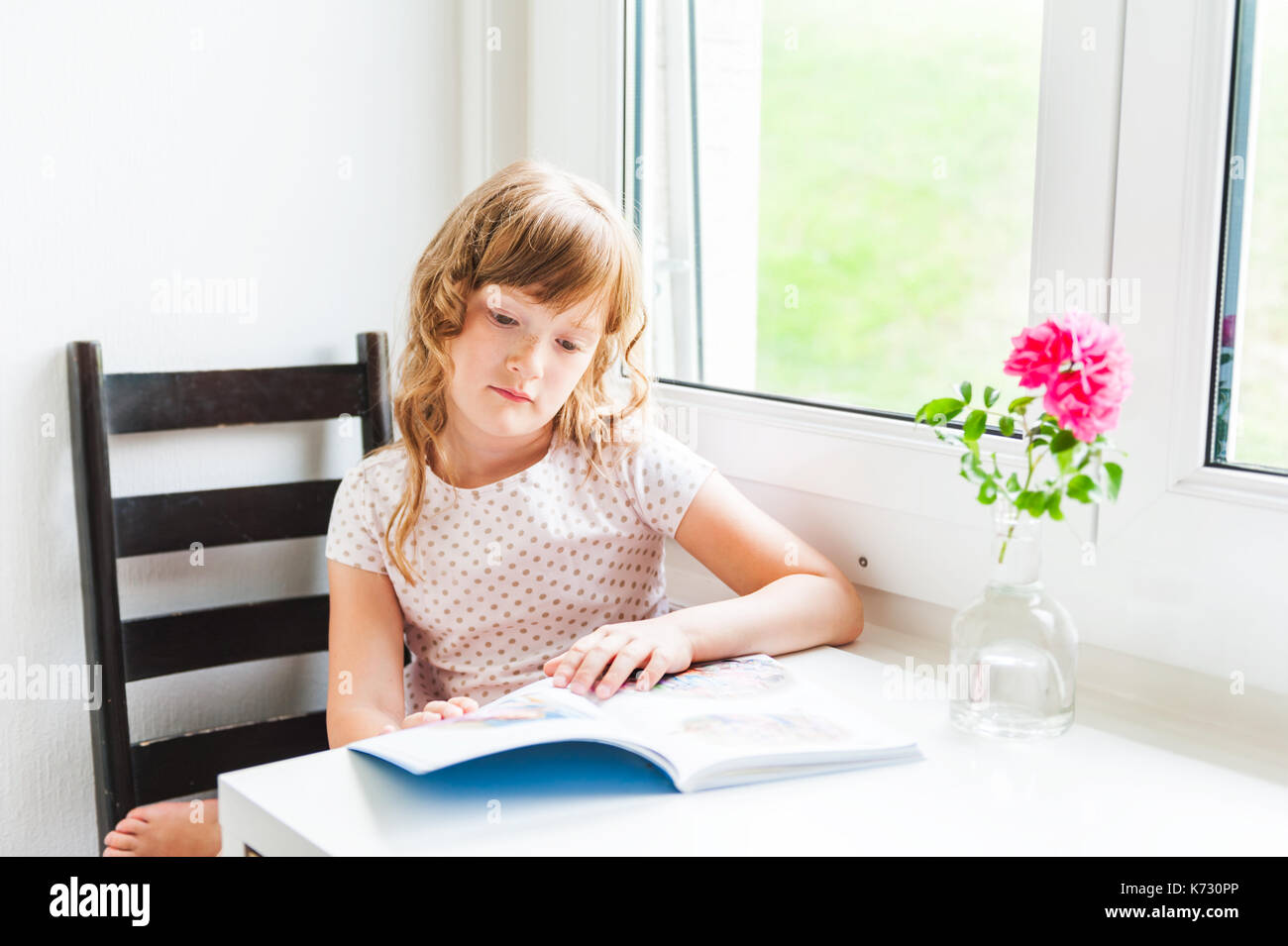 Interior portrait of a cute little girl reading a book Stock Photo