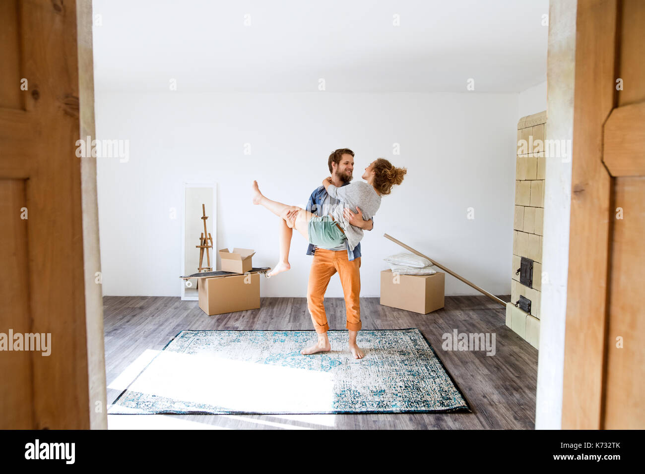 Man carrying woman in his arms, moving in new house. Stock Photo
