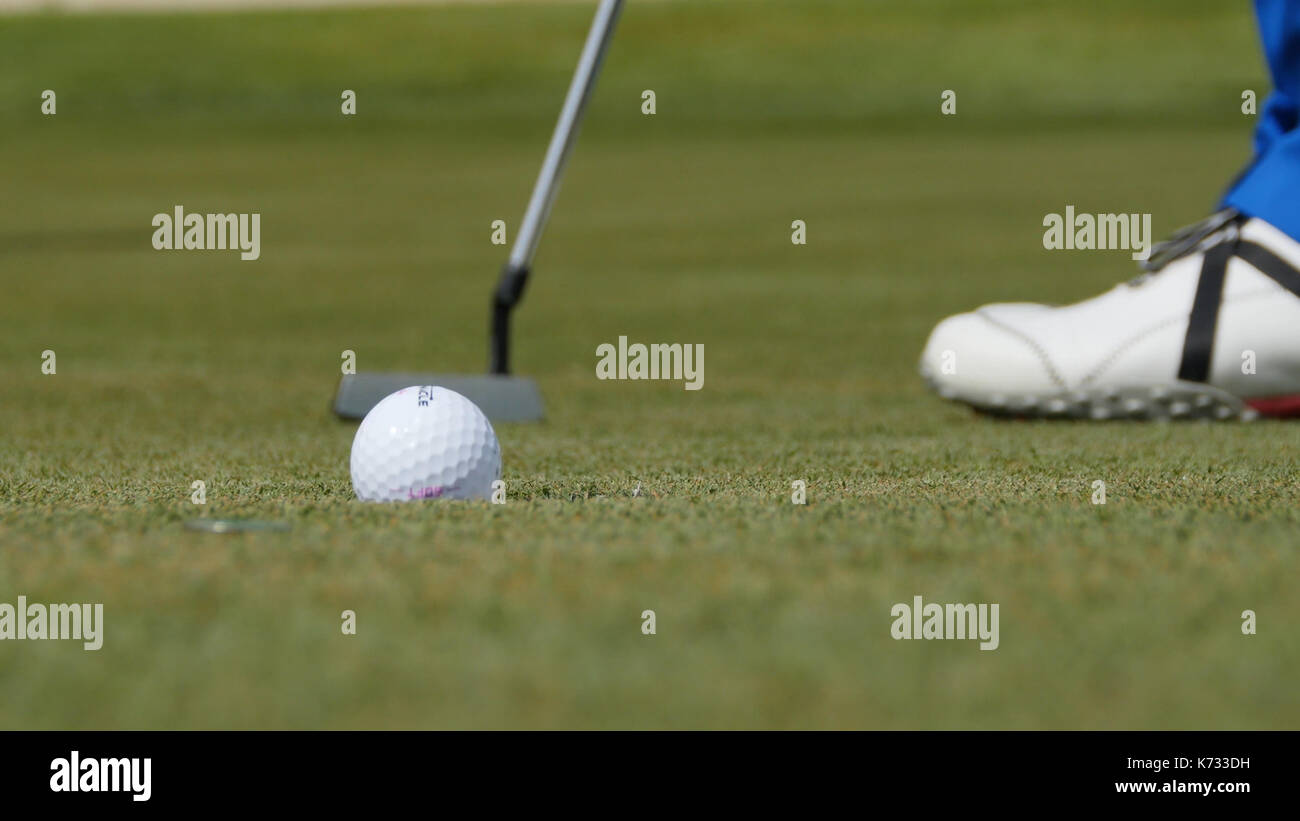 Professional golfer putting ball into the hole. Golf ball by the edge