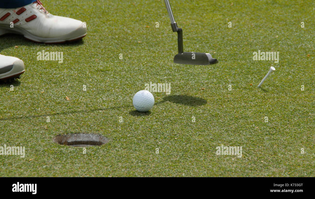 Professional golfer putting ball into the hole. Golf ball by the edge