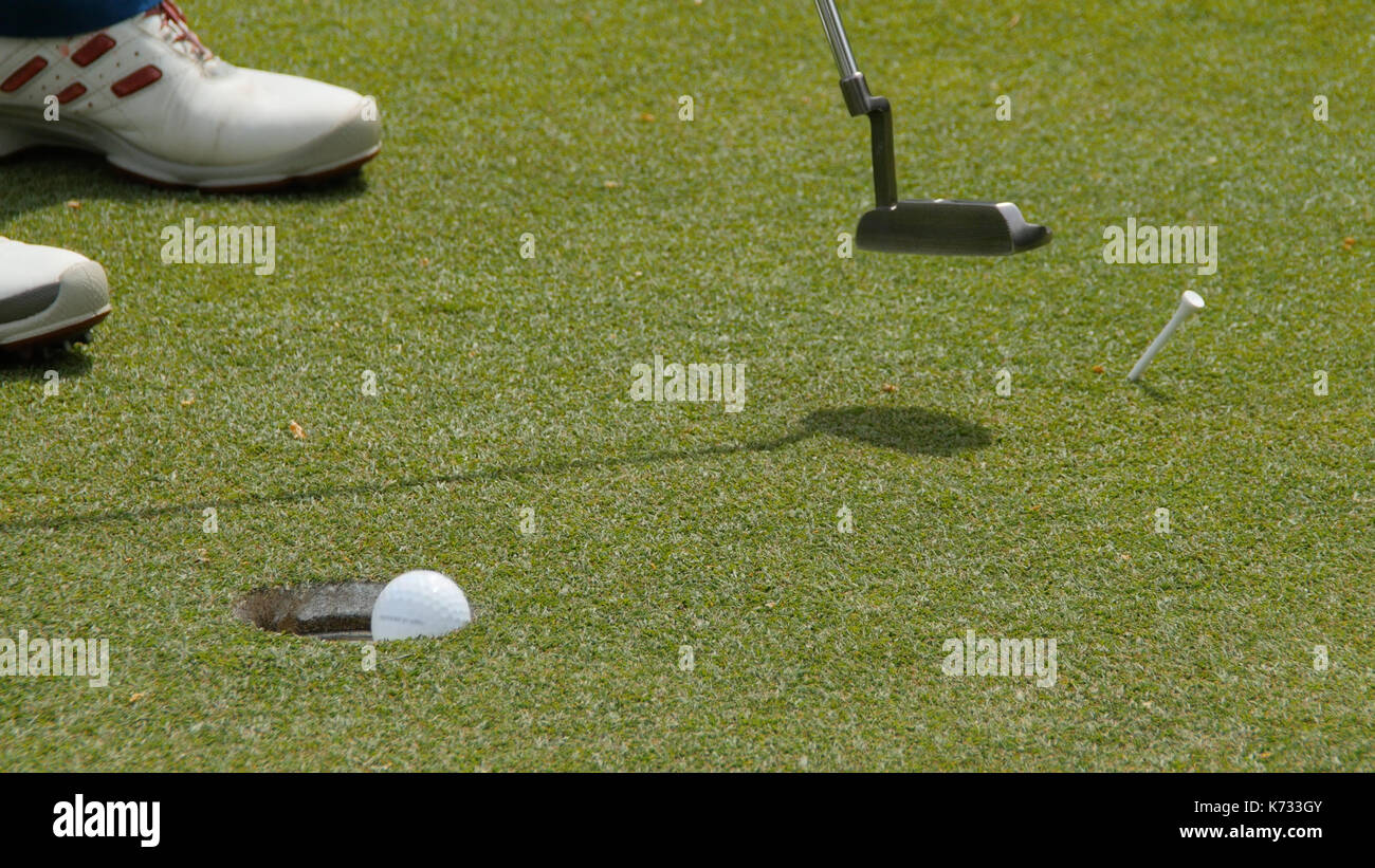Professional golfer putting ball into the hole. Golf ball by the edge
