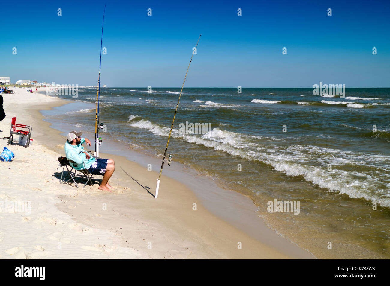 Bearded man surf fishing in the Gulf of Mexico near Gulf Shores, Alabama Stock Photo