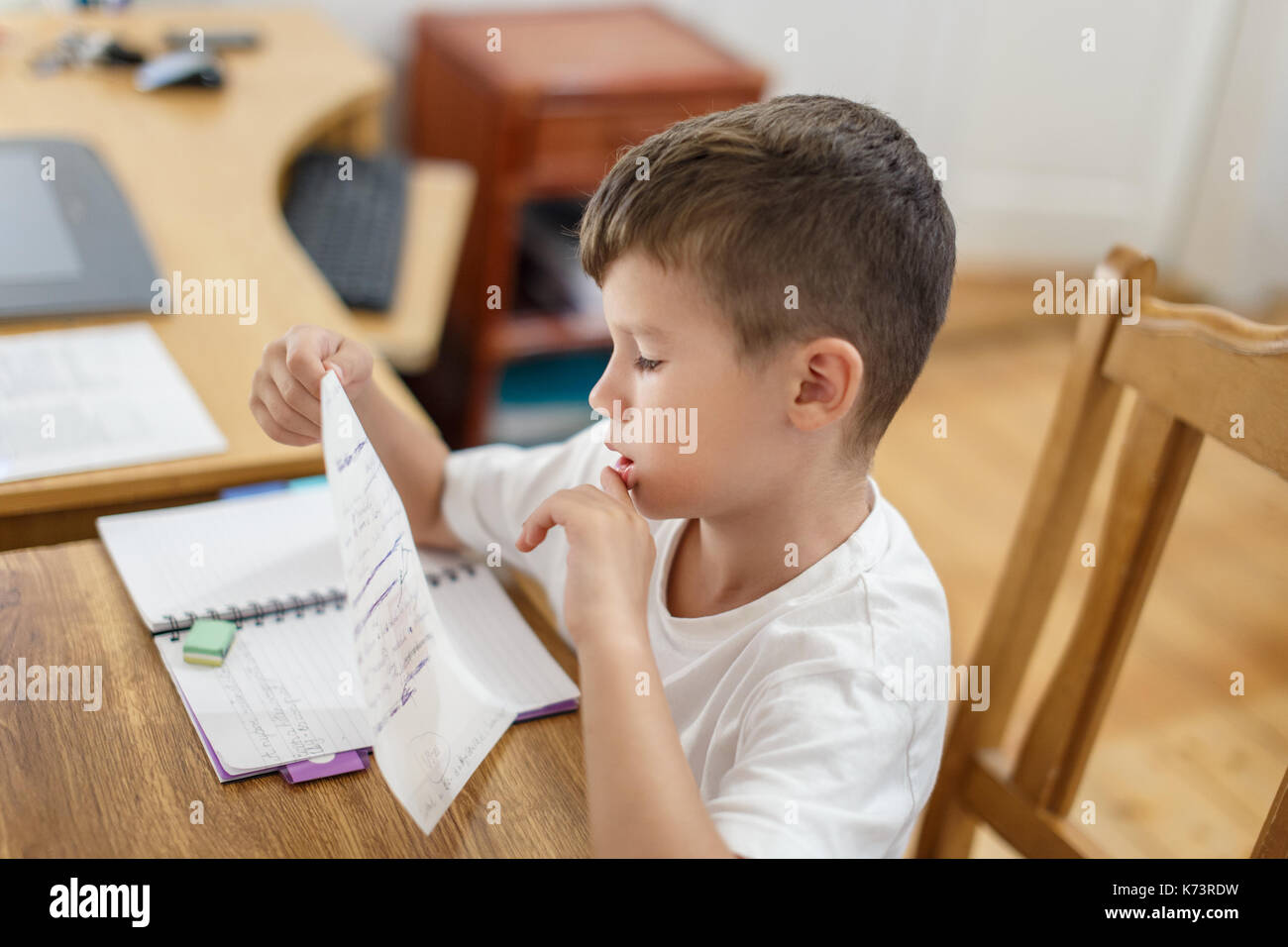 Little schoolboy checking his homework mistakes, thinking Stock Photo