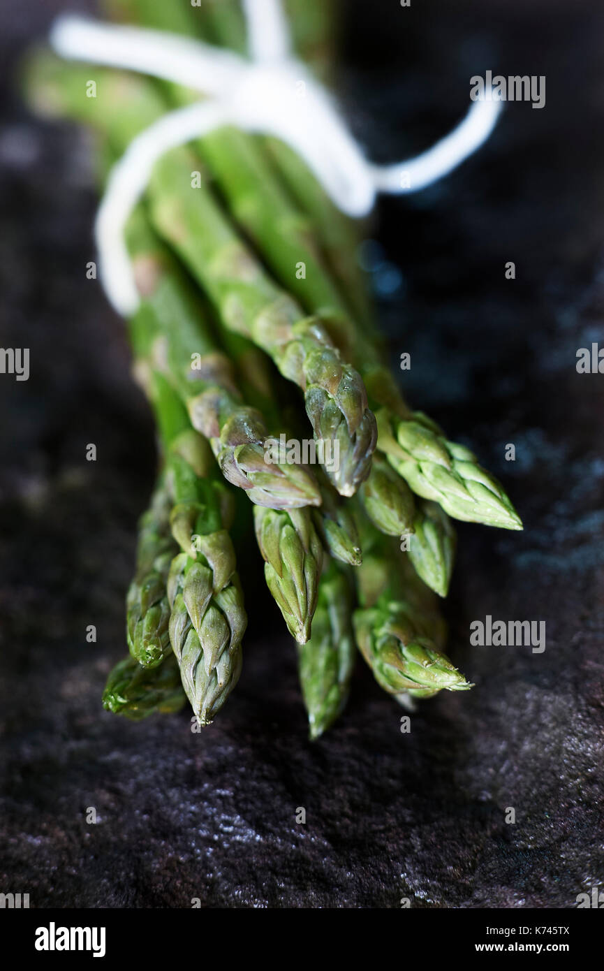 Asparagus bundle straight from the garden allotment wrapped in white string on black work surface. 2017 Stock Photo