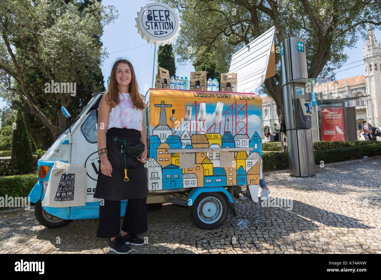 Young woman smiling at the camera standing beside a tuk-tuk beer station Lisbon Portugal Stock Photo