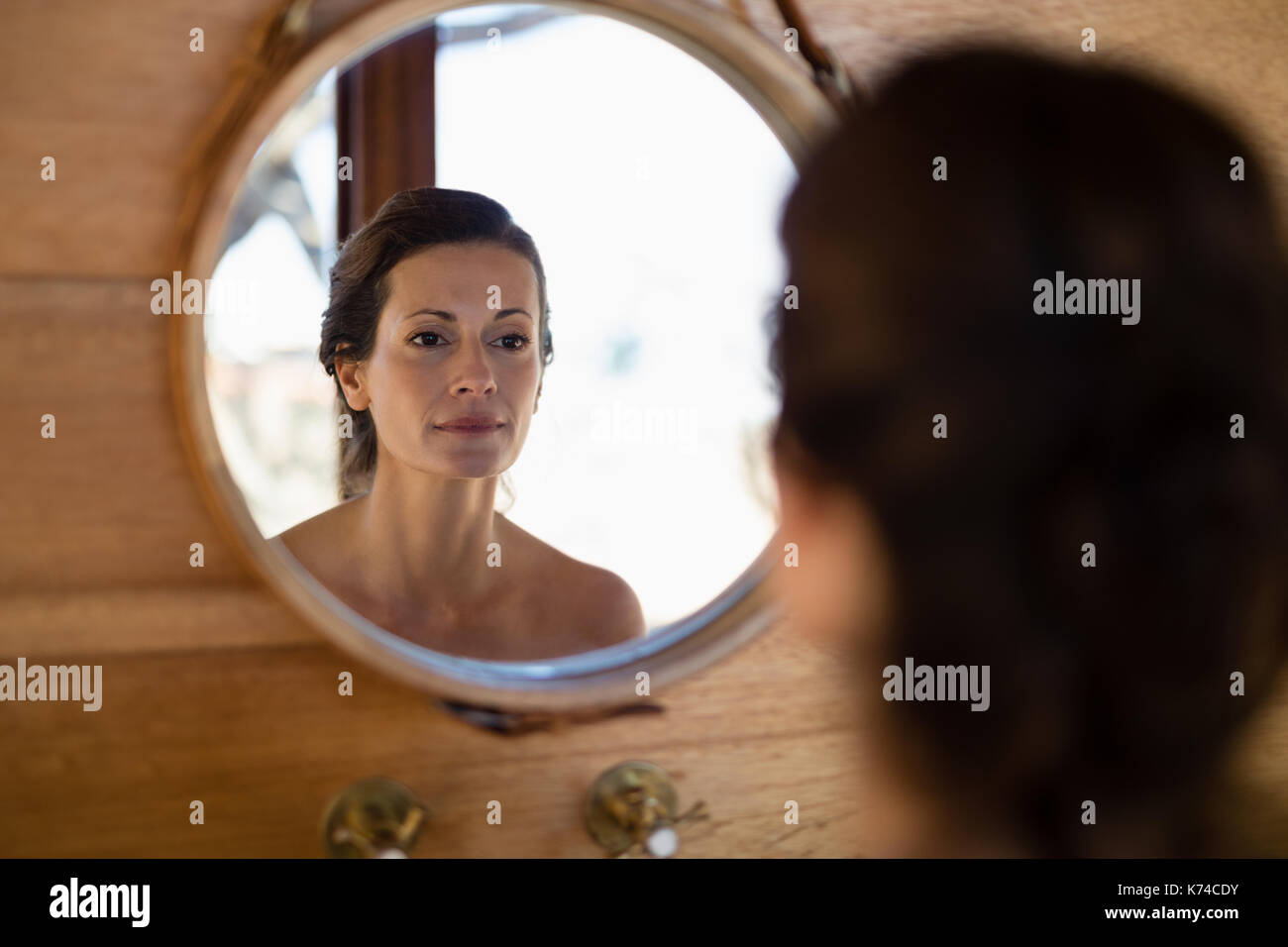Woman looking at mirror in cottage during safari vacation Stock Photo
