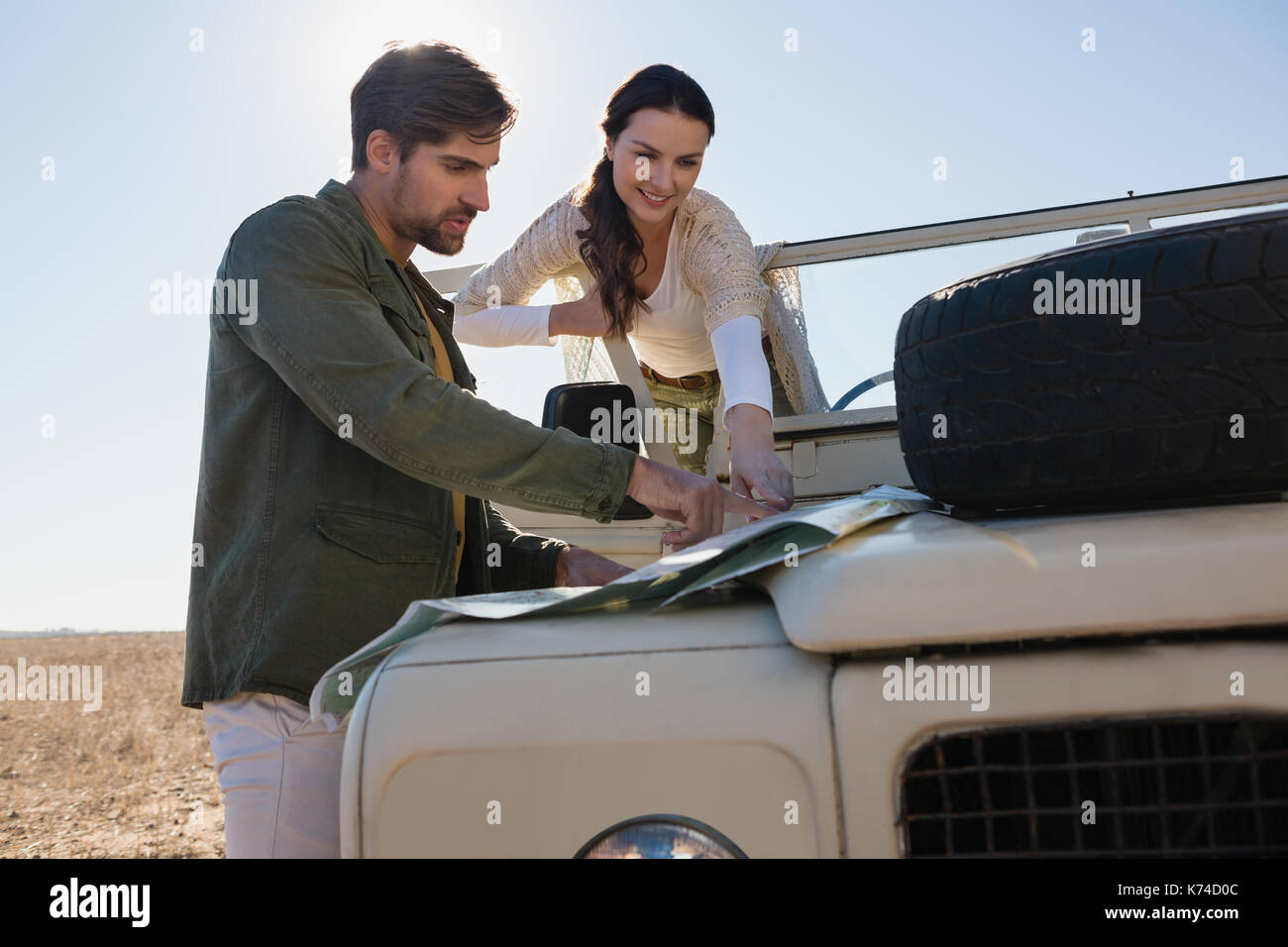 Couple by off road vehicle pointing at map in forest Stock Photo