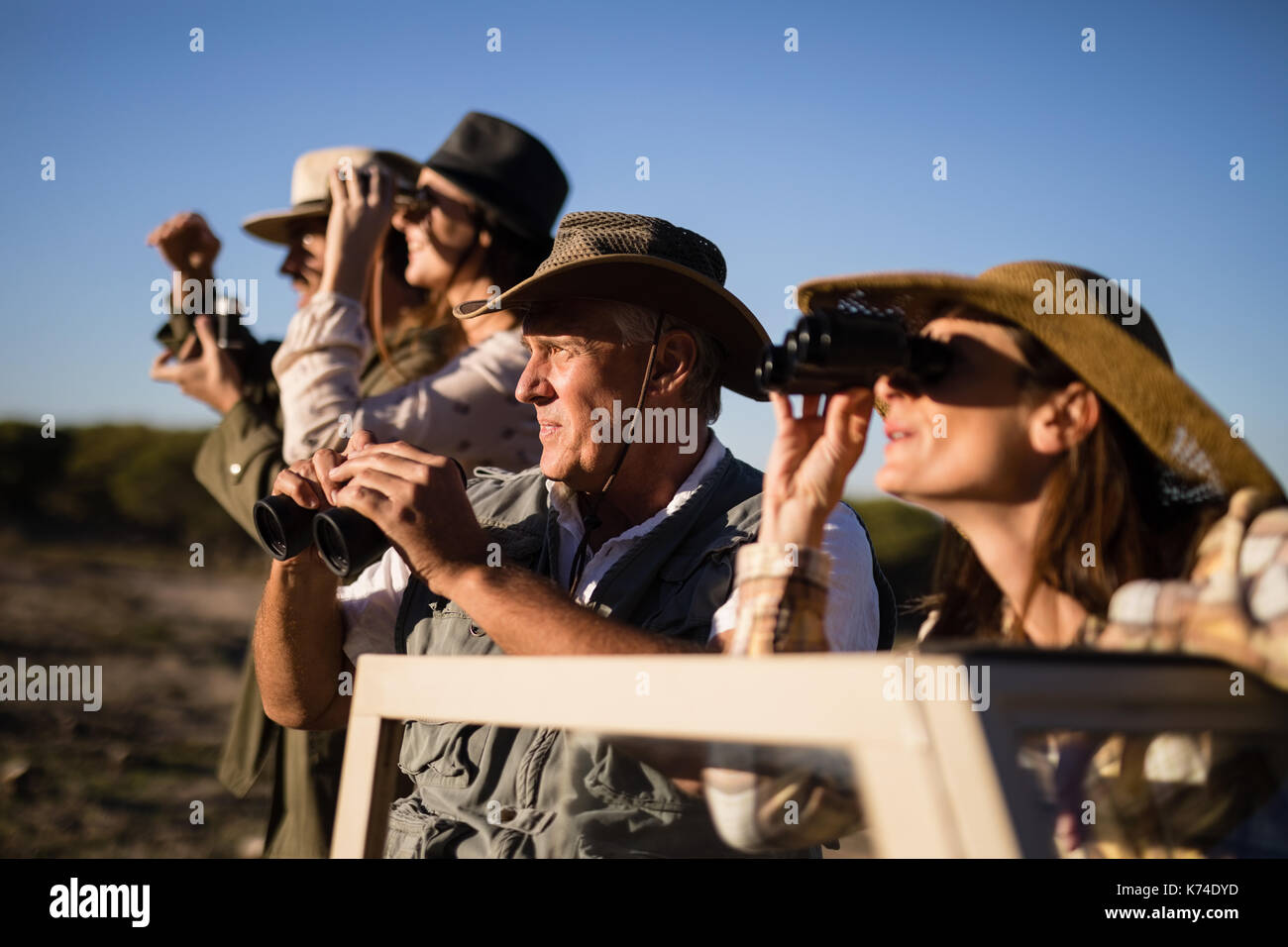 Friends looking through binoculars during safari vacation on a sunny day Stock Photo