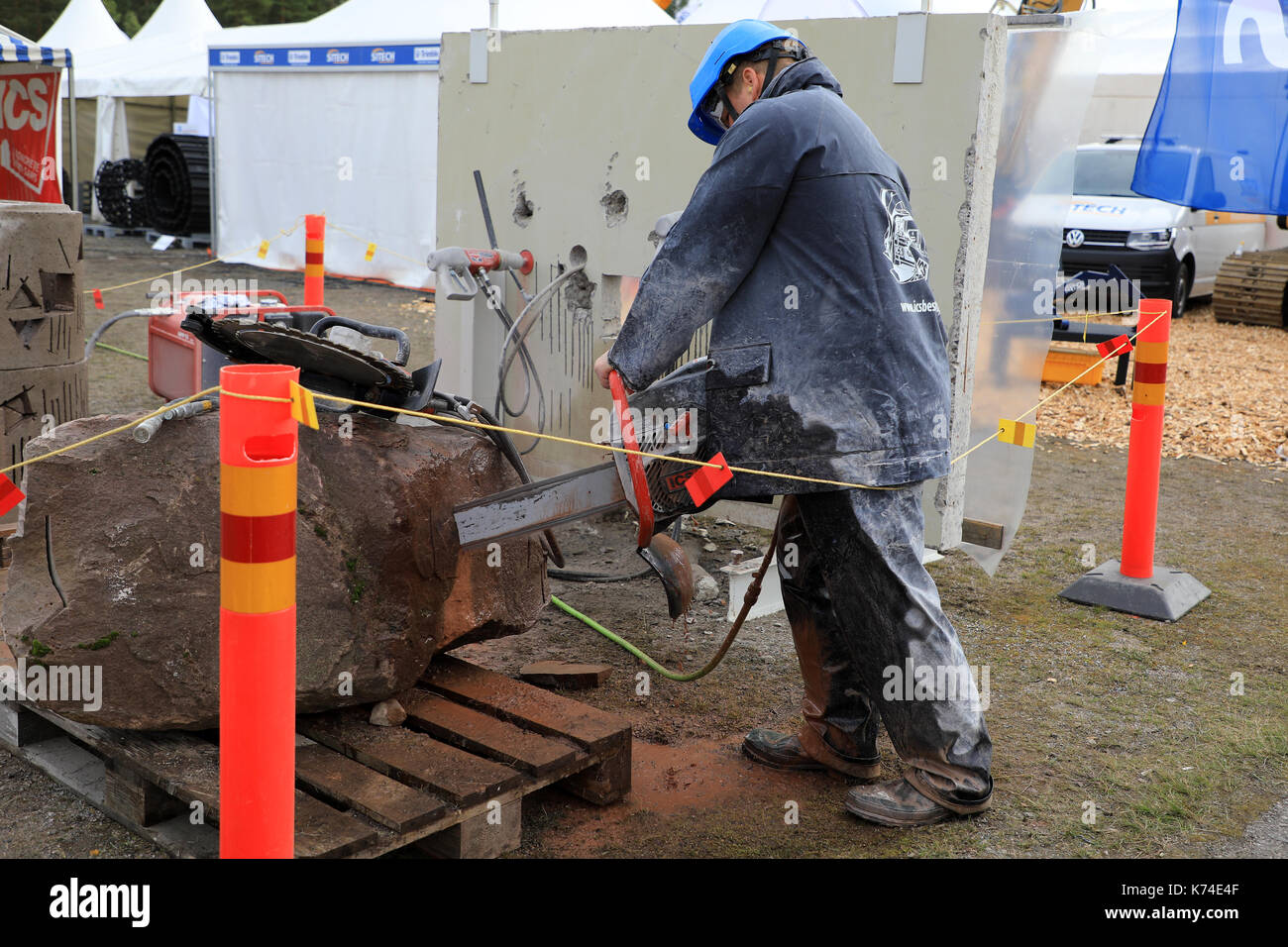 HYVINKAA, FINLAND - SEPTEMBER 8, 2017: Man saws natural granite stone with ICS chain saw on Maxpo 2017. Stock Photo