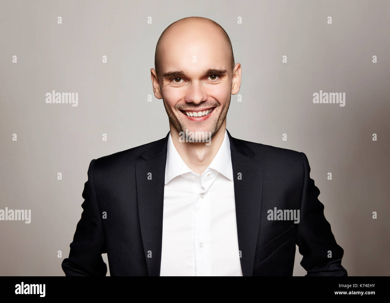 Studio shot of young man looking at the camera. Horizontal format, he is smiling, he is wearing a black jacket. Stock Photo