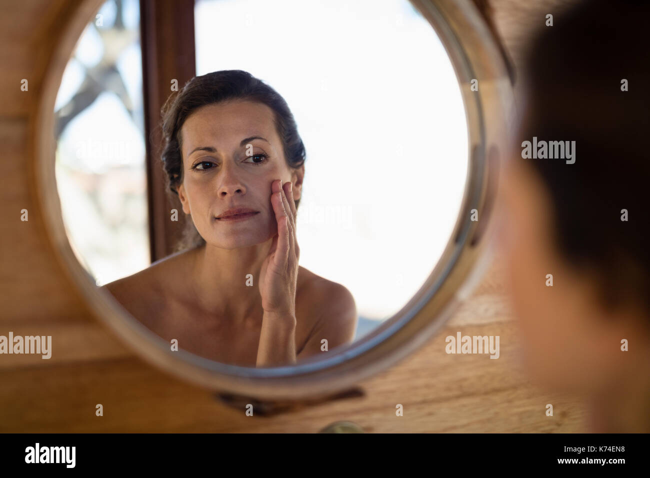 Woman looking at mirror in cottage during safari vacation Stock Photo