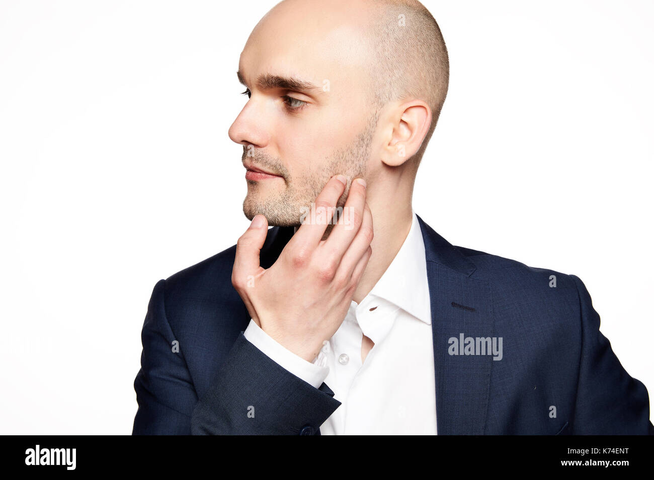 Side view of young man wearing suit. He scratches his chin. Stock Photo