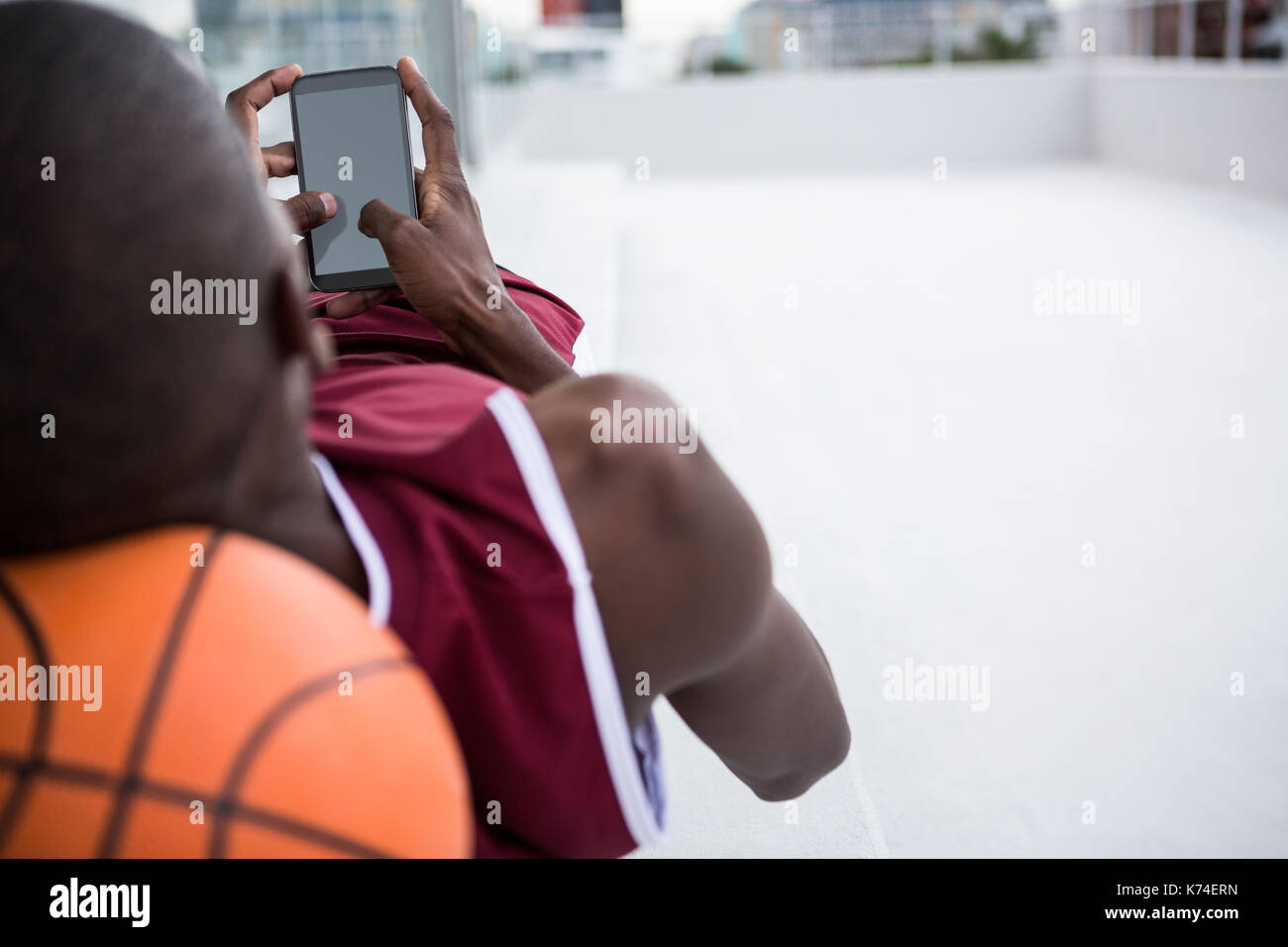 Basketball player using mobile phone while relaxing on terrace Stock Photo