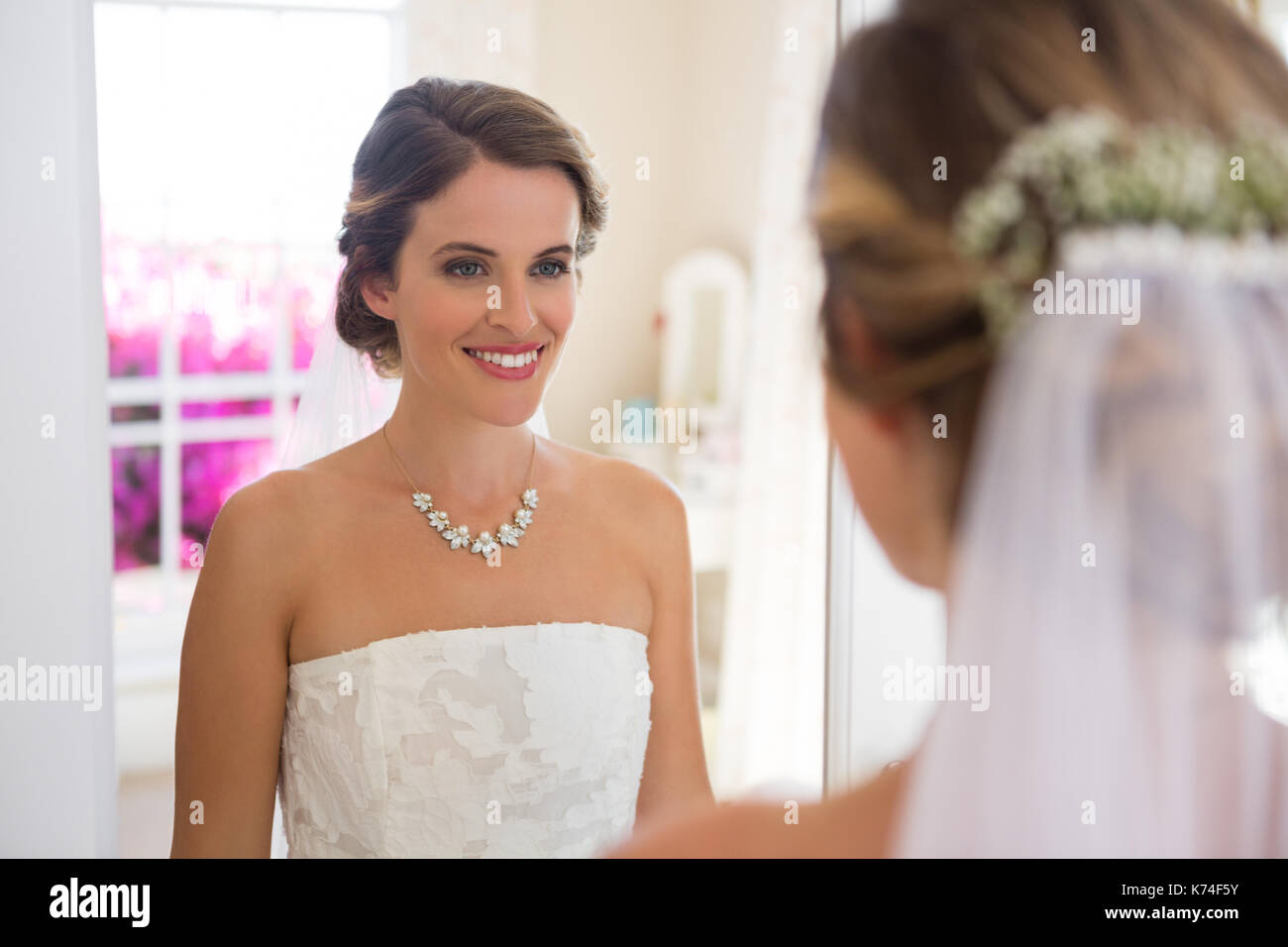 Beautiful bride looking into mirror in fitting room Stock Photo Alamy