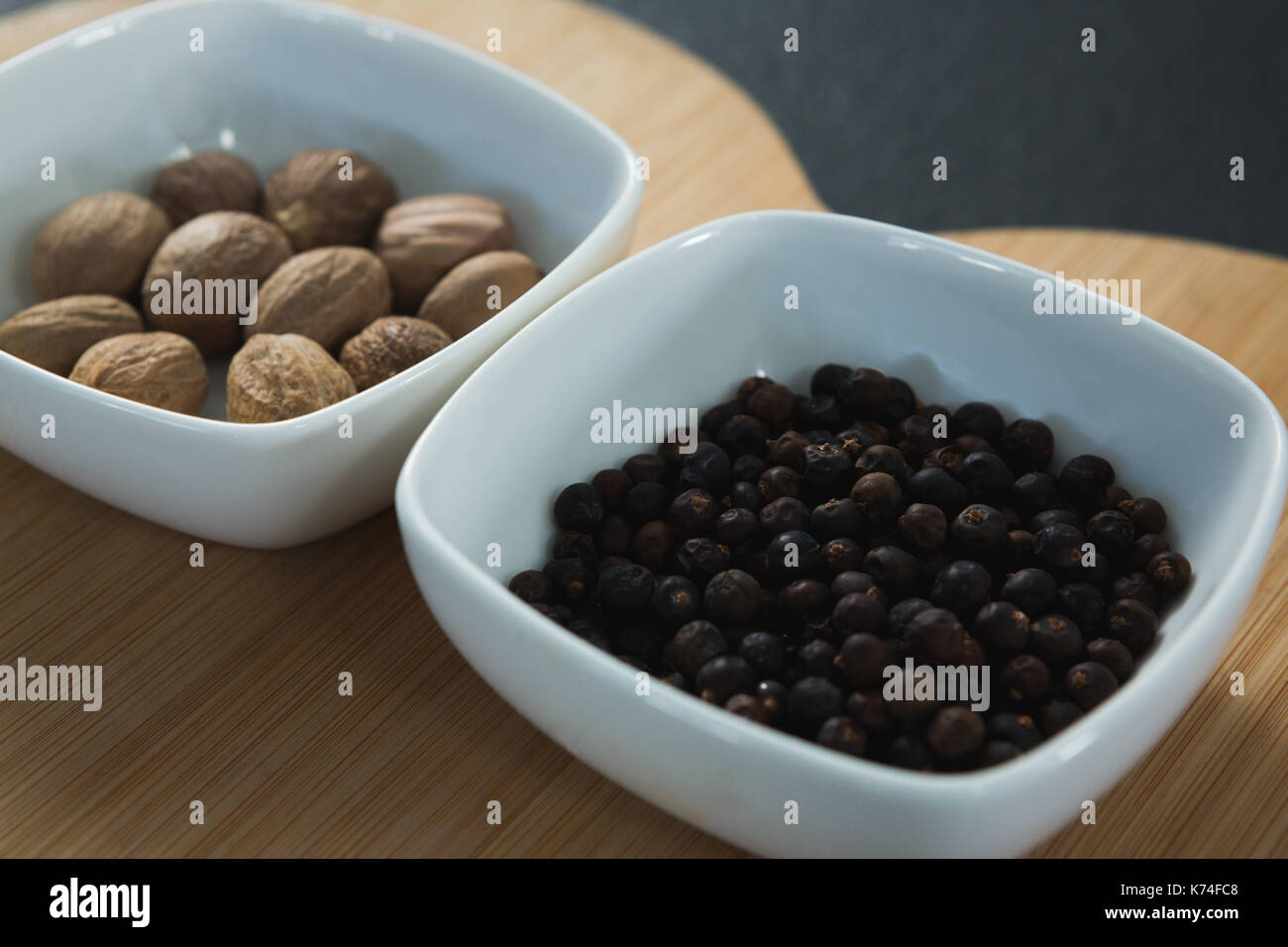 Close-up of nutmegs and black pepper seeds in chopping board Stock Photo