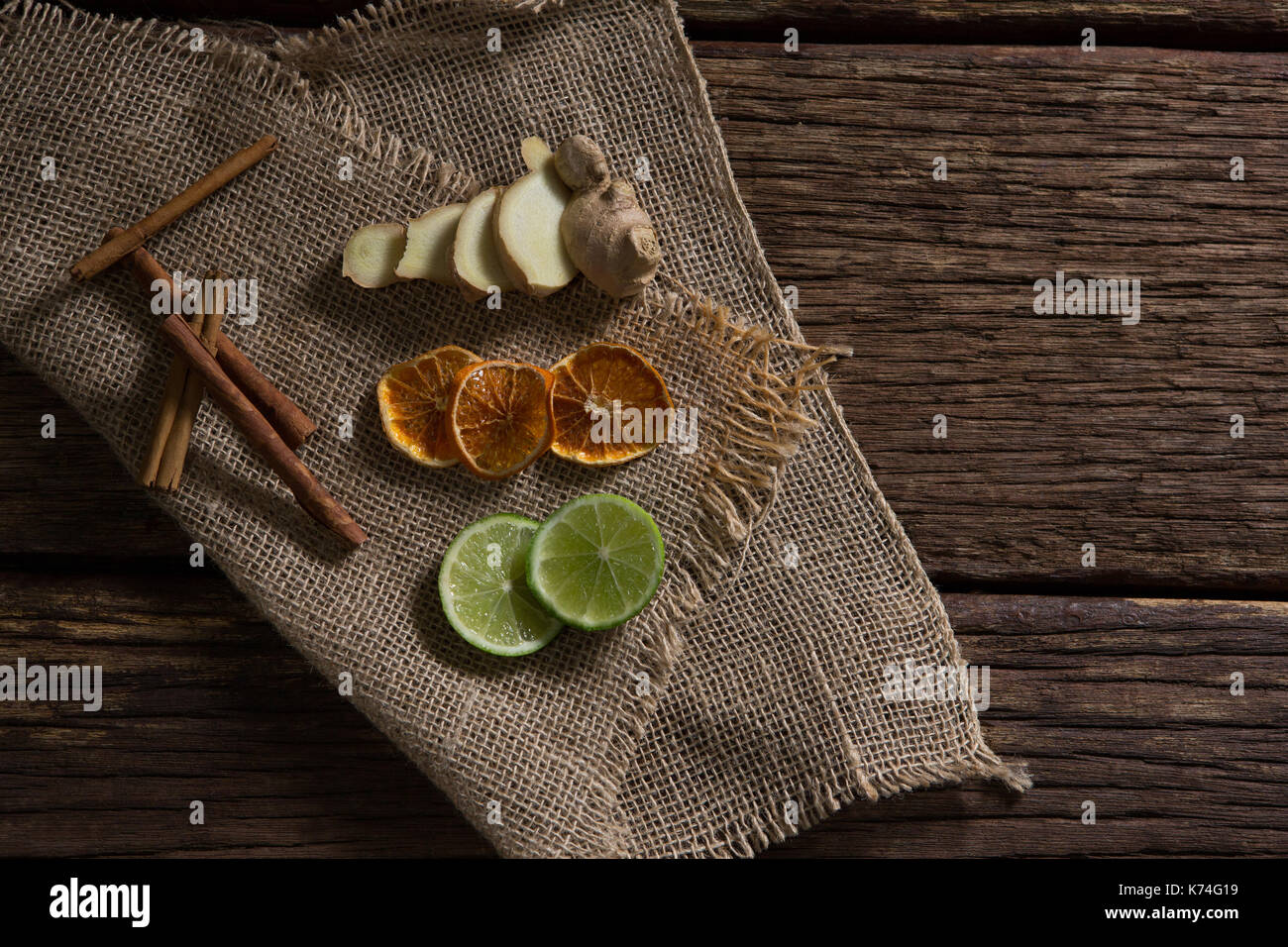 Overhead of sliced ginger, dried orange and lemon with cinnamon stick on textile Stock Photo