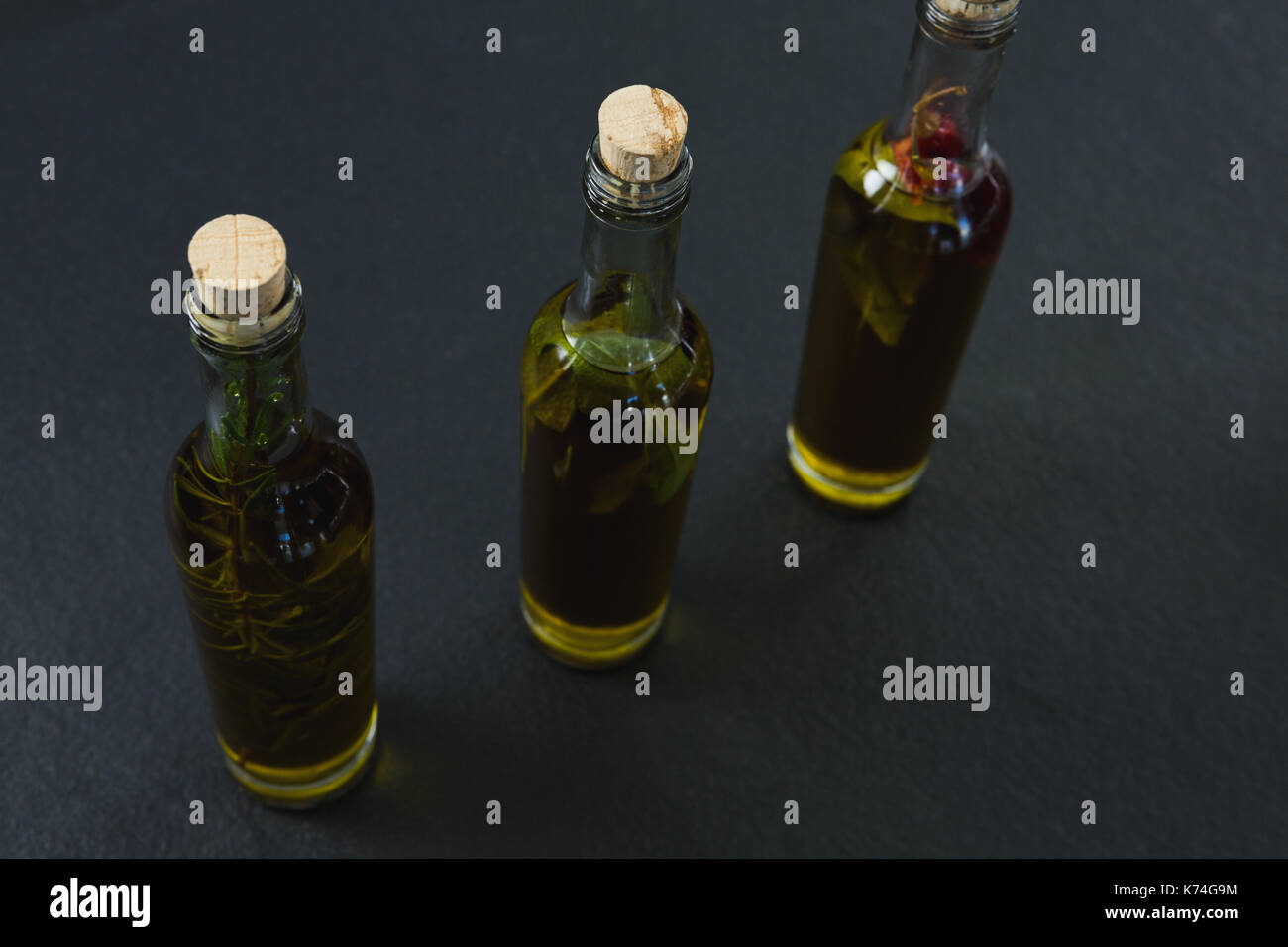 Bottles of olive oil with herbs on black background Stock Photo - Alamy